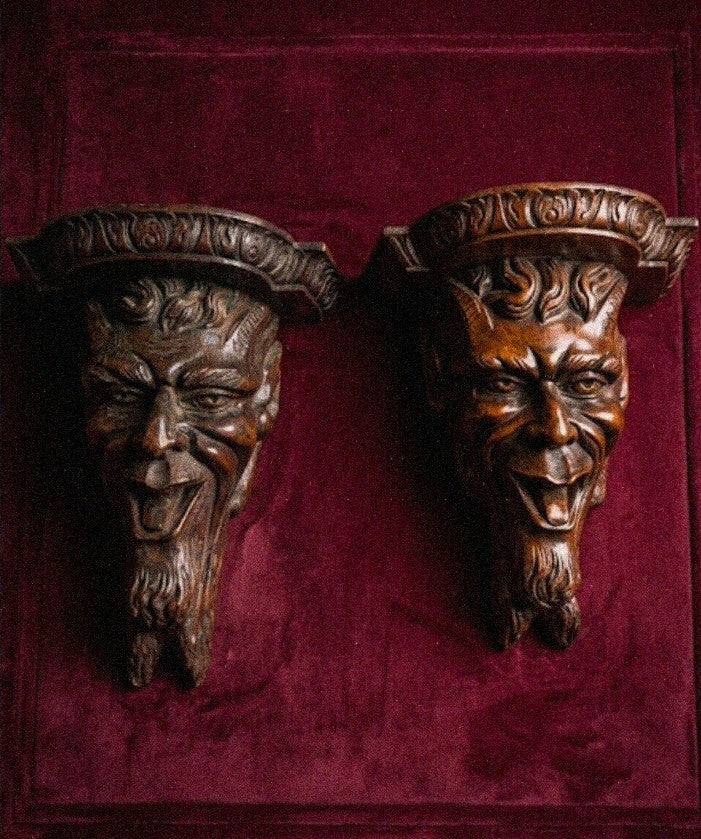 A magnificent pair of 19th century carved wooden wall consoles depicting Satyr faces
